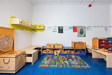 Bauecke in einem Gruppenraum, Teppich mit Straßen und Häusern, Holzbauklötze, Bilder an der Wand, Fahrzeuge