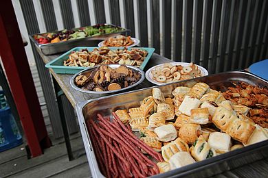 Die Eltern der Kinder haben Essen für ein leckeres Buffet zusammengetragen. Es gibt Trauben, Erdbeeren, Melone, Kekse und Gebäck aus Blätterteig.
