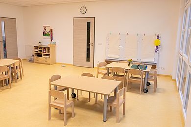 In einem Zimmer stehen kleine Tische und Stühle für die Kinder. An einer Tafel an der Wand wurde Papier angepinnt, das von den Kindern bemalt werden kann.
