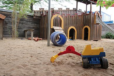 Der Garten mit großem Sandkasten und einem Spielzeugbagger