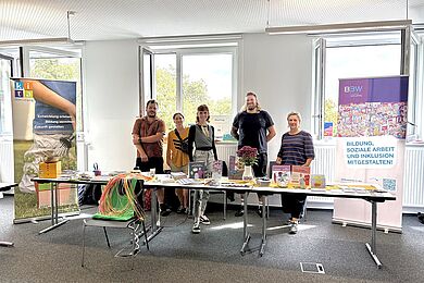 Mitarbeiter*innen der BBW-Leipzig-Gruppe hinter dem Stand bei der Praktikumsbörse. Im Vordergrund ein Tisch mit Info-Material