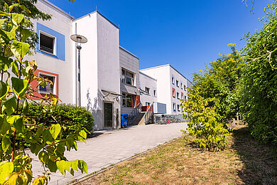 Vorderansicht des Interims in der Reichelstraße: Ein weißes Gebäude. Die Fenster haben blaue und rote Umrandungen