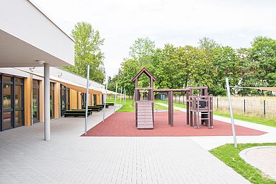 Neben der Terrasse mit den Bänkchen steht ein Klettergerüst aus Holz.