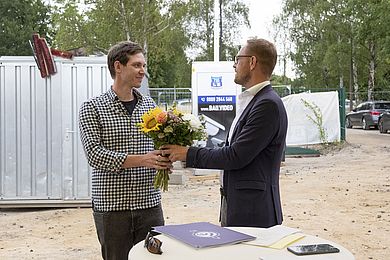 Tobias Schmidt (links) überreicht Blumen an den neuen Leiter der Kita, David Grießmann